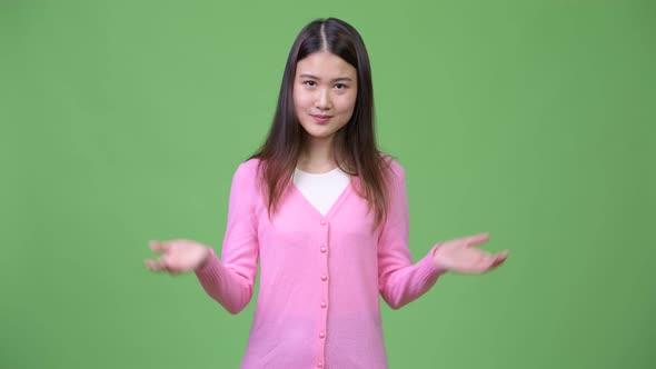 Young Beautiful Asian Woman Shrugging Shoulders