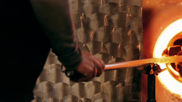Glassblower heating a glass in furnace alt