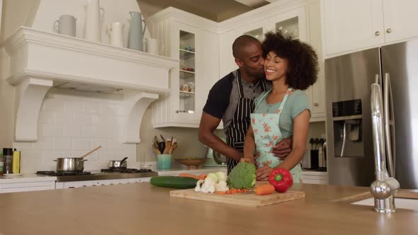 Happy mixed race couple cooking and dancing in their kitchen alt