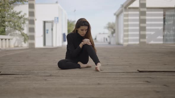 Young Woman Dressed in Black Sits Outdoors Looking Shocked Pushin alt