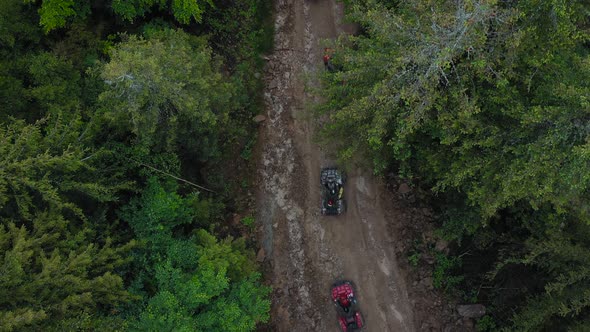 Aerial View of ATV Team Driving Through the Forest in the Mountains alt