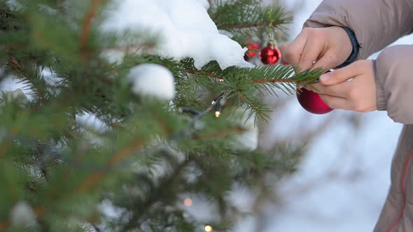 Children's hands in mittens decorate the Christmas tree
