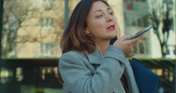 Businesswoman Sending Audio Voice Message on Smartphone Near Modern Office Building Talking to alt