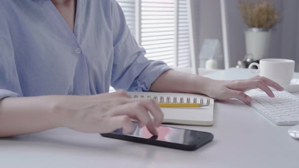 young asian woman work on laptop while sitting in a living room business woman using phone for work. alt