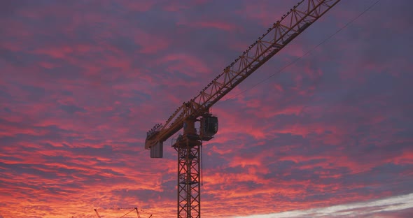 Golden bluish clouds over construction site glow in the light of a sunset alt