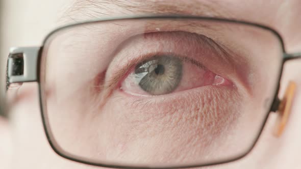 Gray Eye of Middleage Caucasian Male with Diopter Correction Glasses Brightly Lit Closeup