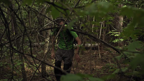 A Young Caucasian Man Makes His Way Through the Forest with a Backpack alt