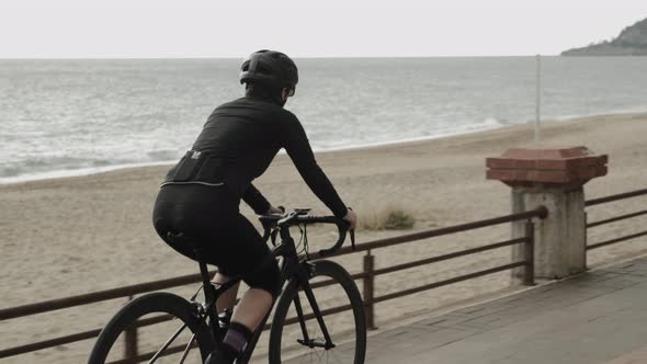 Fit athletic cyclist is spinning pedals on road bike alt