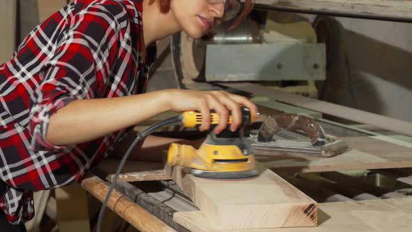 Diligent Female Carpenter Sanding Wood at the Workshop alt
