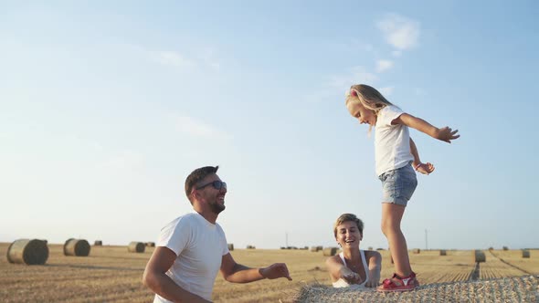 Happy Parents Playing with Little Daughter Jumping Into Hands alt