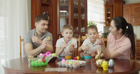 Happy Family Painting Easter Eggs in Kitchen alt