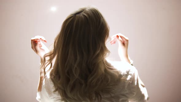A young woman shaking her blond curly hair alt