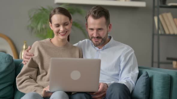 Couple Making Online Video Call on Laptop Sitting on Sofa alt