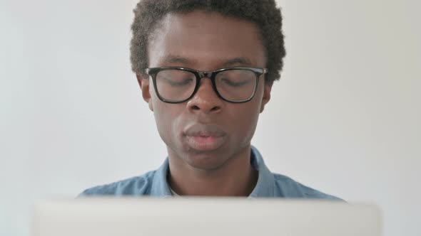 Close Up of Young African Man Reacting to Loss While Using Laptop alt