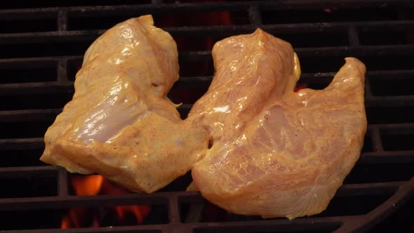 Raw Marinated Chicken Fillet is Frying on the Grill Grid Above the Flames alt