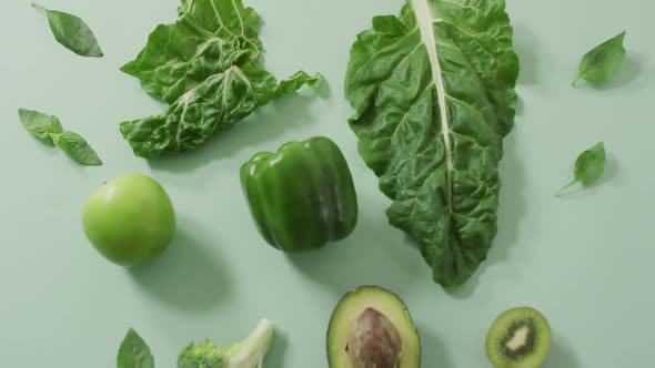 Video of fresh avocado, broccoli, green pepper, apple and green leaves on green background alt