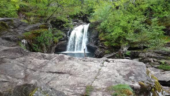 Fly-over drone shot of mountain waterfall with river alt