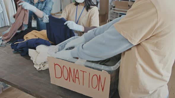 Volunteers Sorting out Donation Containers with Clothes alt
