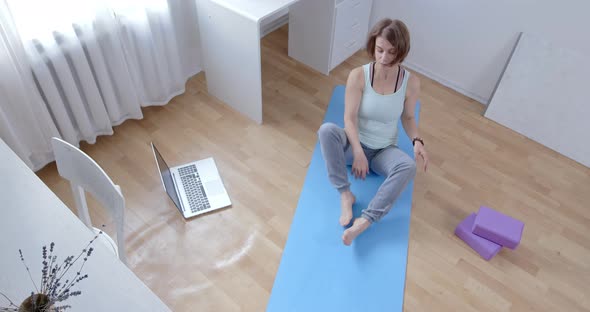 Woman doing yoga online at home. Lessons by video communication via laptop remotely. alt