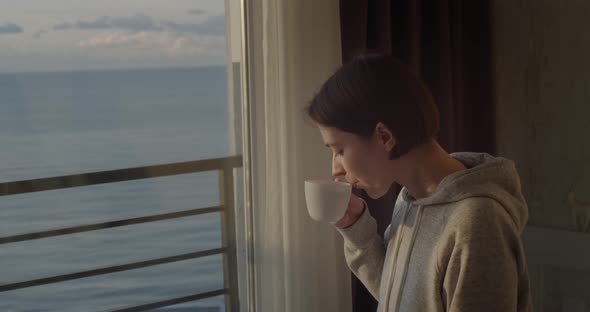 Side Portrait of Young Girl Drinking Tea Looking Outside and Smiling