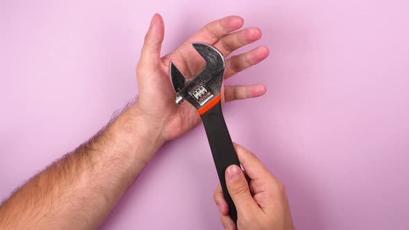 Young man's hands hold adjustable metal wrench construction tool for plumbing repair