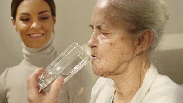 Female Caregiver Giving Pills to Old Woman