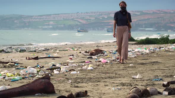 Woman Wearing Mask Walking On The Beach With Garbage And Coconut Shells. - wide shot alt