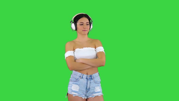 Young Hispanic Woman Wearing Headphones Serious Face Thinking on a Green Screen alt
