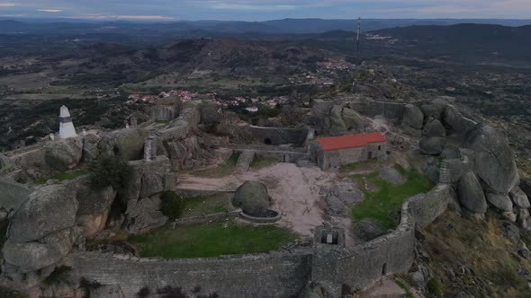 Drone flies over Monsanto castle ruins and surrounding landscape at sunrise, Portugal. Aerial forwar alt