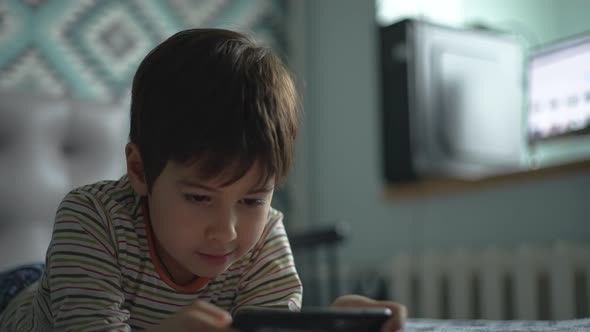 The Boy is Actively Playing Smartphone Alone in the Room