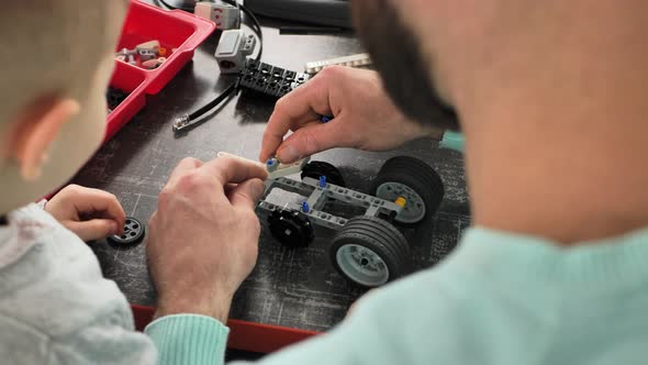 Closeup of the Hands of a Father and Son Who Create a Robot in the Robotics Club