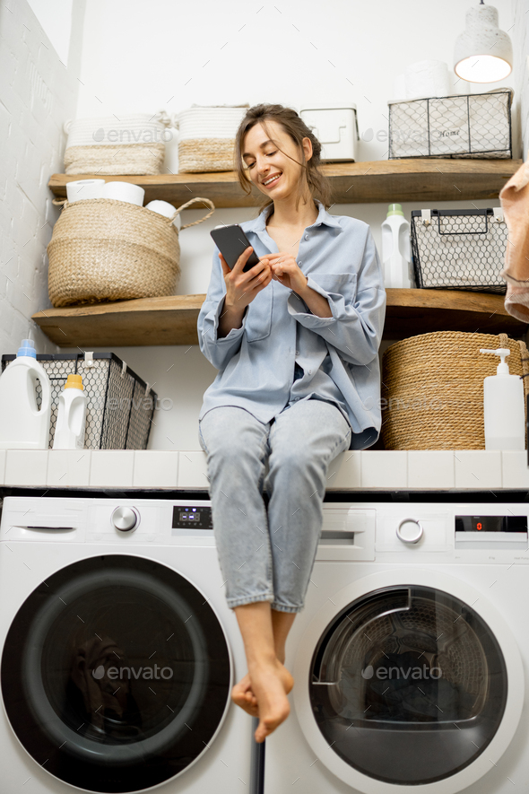 Woman With Phone In The Laundry Room Stock Photo By Rosshelen Photodune
