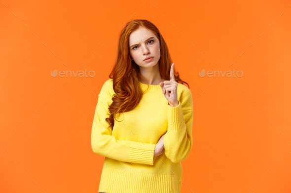 Redhead girl express disapproval as shaking her finger at someone with disappointed angry face