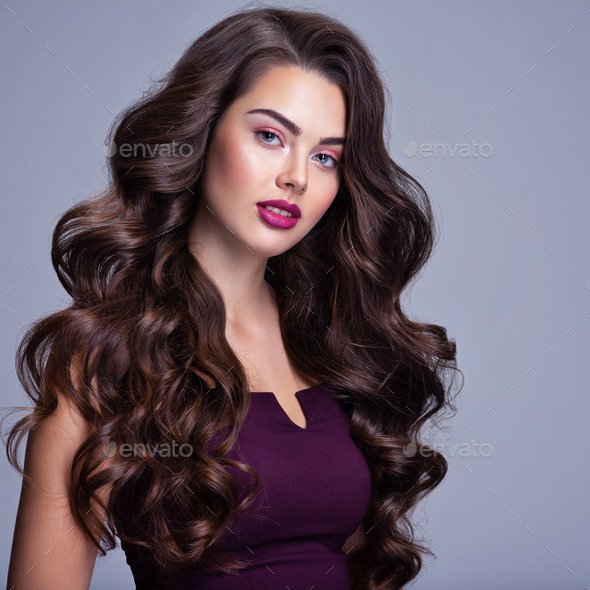 Fashion model with wavy hairstyle. Attractive young girl with curly hair  posing at studio. Stock Photo by valuavitaly