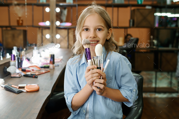 Little girl shows cosmetic in makeup salon