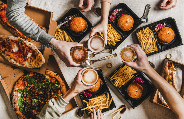 People clinking glasses with beer and eating burgers and pizza - Stock Photo - Images