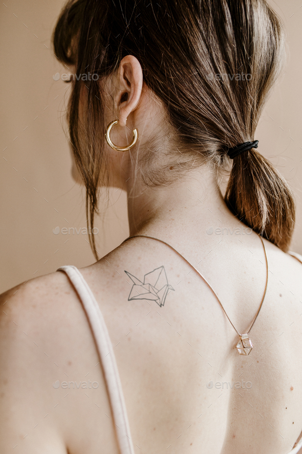 Woman with a paper bird tattoo on her shoulder