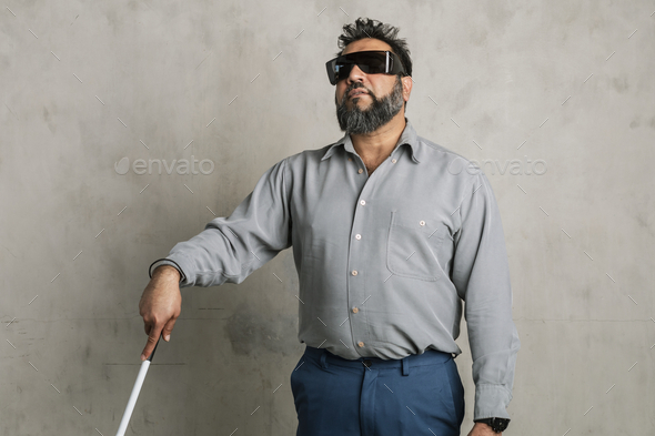 Blind Indian man wearing black goggles and using a white cane