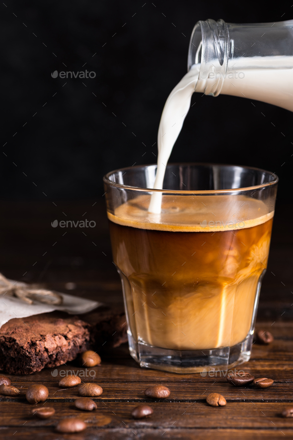 latte macchiato, pouring espresso in glass, pitcher with coffee, milk foam,  energy and caffeine Stock Photo by LightFieldStudios