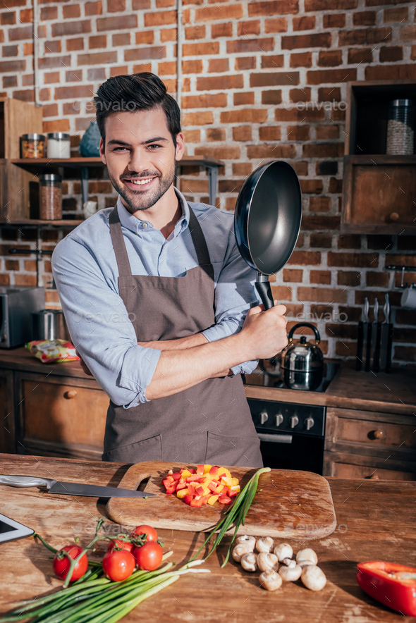 handsome young man posing with frying pan at kitchen Stock Photo by ...