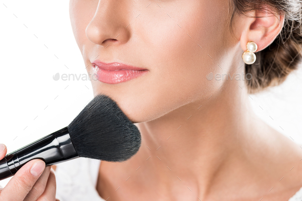 partial view of makeup artist applying powder on models face using makeup brush isolated on white