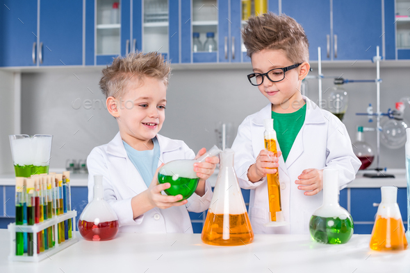 Smiling little boys in lab coats making experiment in chemical ...