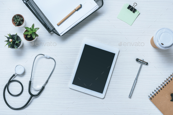 top view of digital tablet with blank screen, stethoscope, reflex hammer and paper cup of coffee on