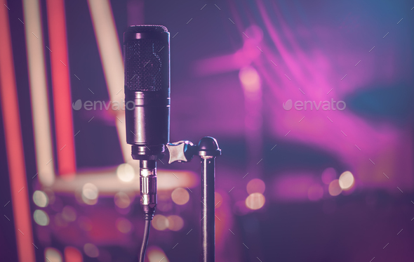 Microphone in recording Studio or concert hall close-up, with drum set on  background out of focus. Stock Photo by puhimec