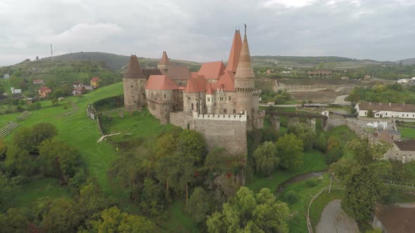 Aerial of Corvin Castle surrounded by green trees alt