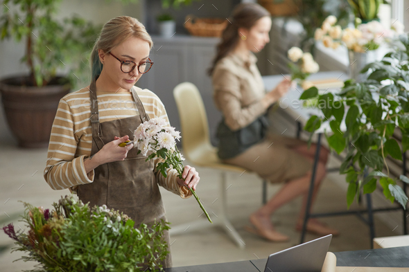 Female Florist Cutting Flowers in Workshop Stock Photo by seventyfourimages