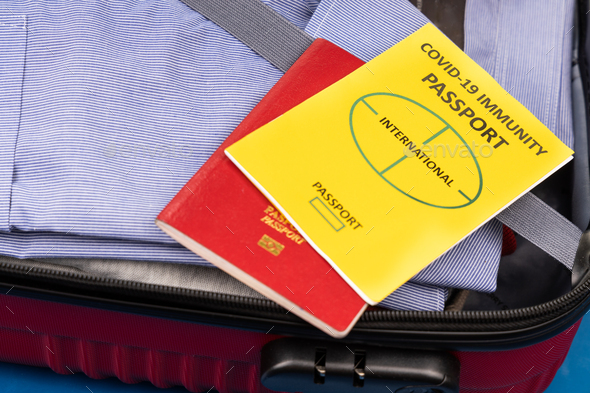 Concept of covid-19 Immunity Passport for international travel with clothes packed in luggage bag