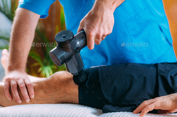 Therapist Treating Patient’s Quadriceps Muscle with Massage Gun