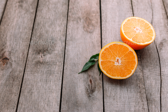 Halves of orange fruit on gray wooden background. Orange pulp and green leaves - Stock Photo - Images