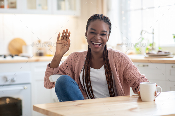 Cheerful young Black woman in loungewear drinking cup of morning coffee in  her kitchen and laughing at funny memes on smartphone screen Stock Photo -  Alamy